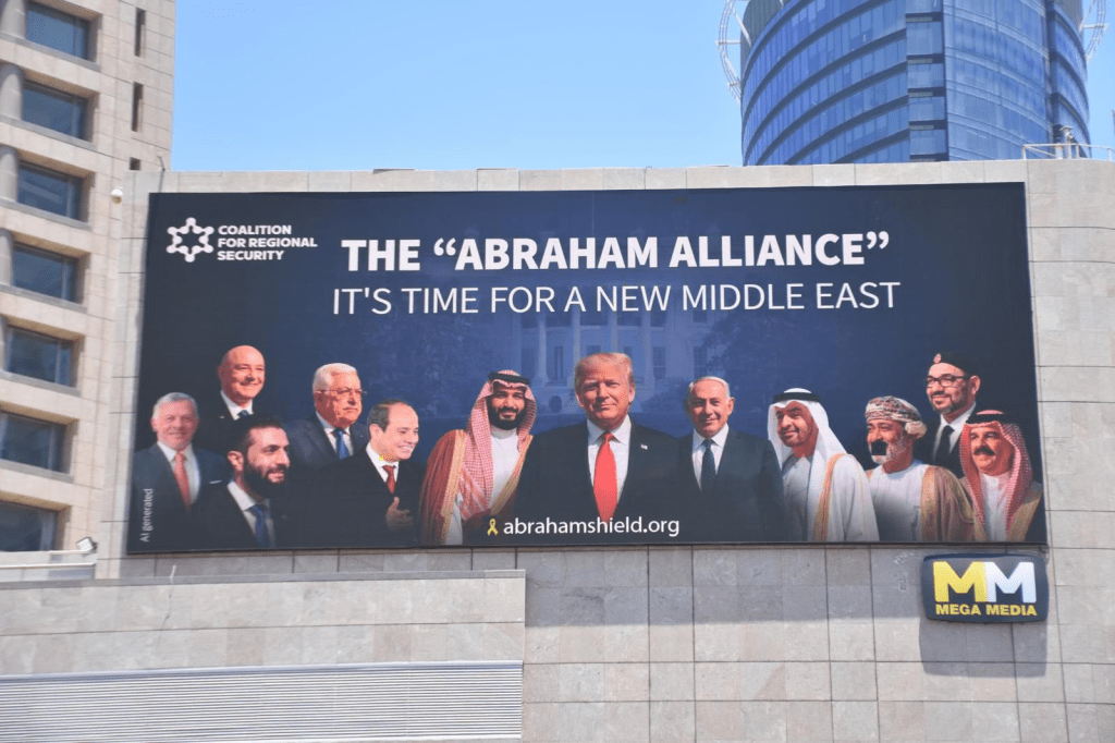 A large billboard promoting the Abraham Alliance, featuring various political figures including Donald Trump, with the text 'THE "ABRAHAM ALLIANCE" IT'S TIME FOR A NEW MIDDLE EAST'.